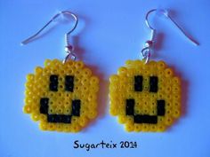 a pair of earrings made out of yellow beads with an emo face on it