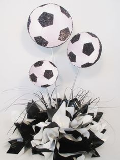 three black and white soccer balls on top of each other with streamers in the middle