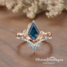 an engagement ring with blue topazte and diamond accents on a wooden table next to flowers