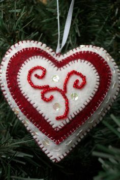 a red and white heart ornament hanging from a christmas tree