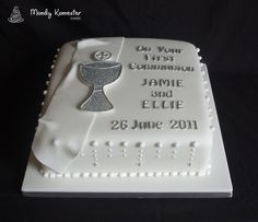 a white cake with a silver cross on it's side and the words on your first communion, jamie and ellie 25th june 2011