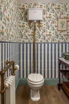 a bathroom with blue and white wallpaper, gold fixtures and a toilet in the corner