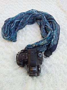 a camera is laying on the floor next to a scarf