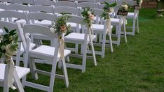 rows of white folding chairs with flowers and ribbons tied to the seats are lined up on green grass