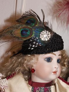 a doll wearing a black hat with feathers on it's head and blue eyes