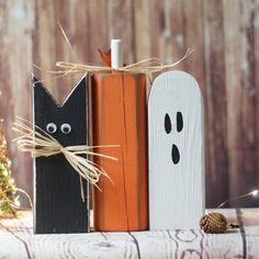 two halloween decorations made out of wood and painted black, white and orange with eyes on them