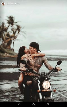 a man riding on the back of a motorcycle next to a woman kissing her cheek