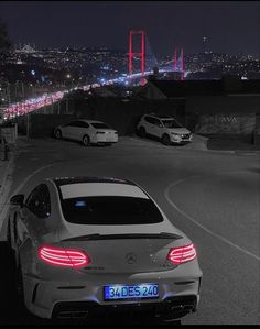 a car parked on the side of a road next to a suspension bridge at night