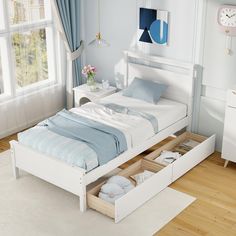 a white bed with two drawers underneath it in a blue and white themed bedroom area