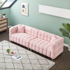 a pink couch sitting on top of a wooden floor next to a white and black rug