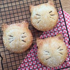 three pastries with faces drawn on them sitting on a cooling rack