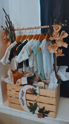 a wooden crate filled with baby clothes and stuffed animals sitting on top of a table