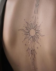 the back of a woman's stomach with a sun tattoo on her left side