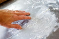 a person is kneading dough on a baking sheet with their hand in the middle