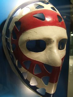 a red and white mask on display in a glass case