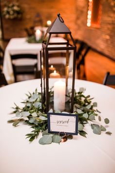 a candle is lit on top of a table with greenery