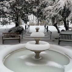 two benches and a fountain covered in snow