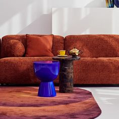 a living room with a couch, coffee table and vases on the floor in front of it