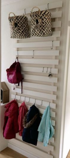 a wall mounted coat rack with several coats hanging from it's hooks and two purses