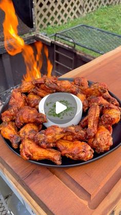 chicken wings being served on a black plate over an open fire pit in the back yard