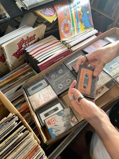 a person is looking at some records in a box on a table with other records