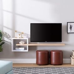 a flat screen tv sitting on top of a wooden shelf next to two stools