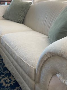 a white couch with pillows on it in front of a blue and white carpeted floor