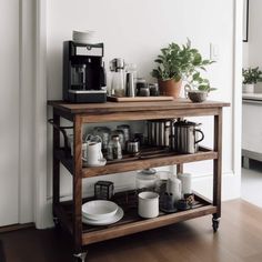 a wooden table topped with lots of coffee cups and saucers next to a potted plant