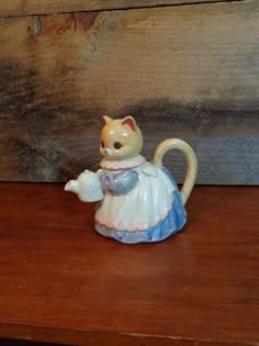 a ceramic cat figurine sitting on top of a wooden table next to a wall