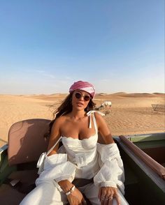 a woman sitting in the back of a pick up truck on top of a sandy beach