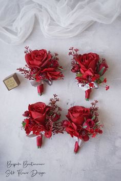 four red flowers are arranged on a white surface