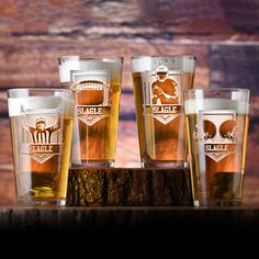 four glasses filled with beer sitting on top of a wooden table next to each other