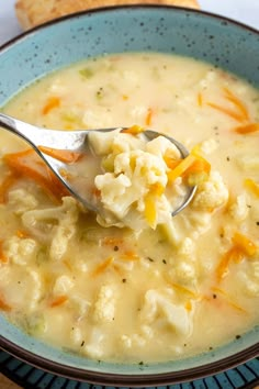 a spoonful of soup in a blue bowl with crackers on the table behind it