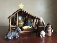 three crocheted nativity figurines sitting in front of a wooden structure