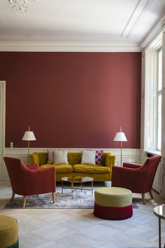 a living room with red walls and yellow chairs in the corner, two lamps on either side of the couch