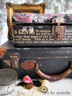 an old suitcase with writing on it sitting next to other antique items and decorations in front of snow - covered trees