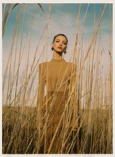 a woman standing in tall grass with her eyes closed