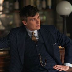 a man in a suit and tie sitting at a bar with his hands on his hips