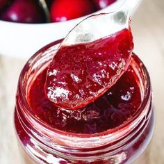 a spoon full of cranberry sauce sitting on top of a jar