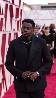 a man in a black suit standing on a red carpet