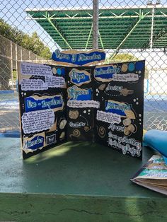 an open book sitting on top of a green table next to a blue ball field