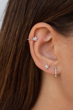 a close up of a woman's ear with three small diamond studs on it