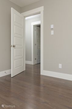 an empty room with hard wood floors and white doors in the center, leading into another room