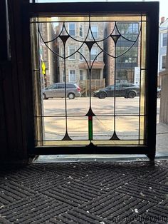 a stained glass window on the side of a building with cars parked in the street behind it