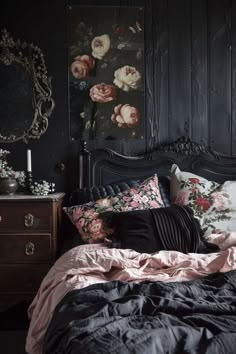 a bed with black sheets and pink flowers on the headboard is next to a dresser