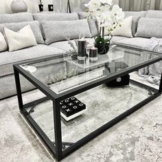 a glass coffee table sitting on top of a carpeted floor next to a couch