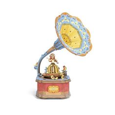 an old fashioned clock on top of a red and blue stand with a gold bell