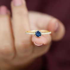 a close up of a person holding a ring with a blue stone