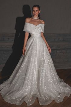 a woman in a white wedding dress standing on a wooden floor with her shadow behind her