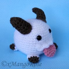 a crocheted white and black dog with a pink nose on a blue background